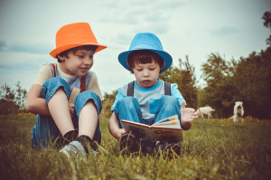 kids sitting in a field reading a book
