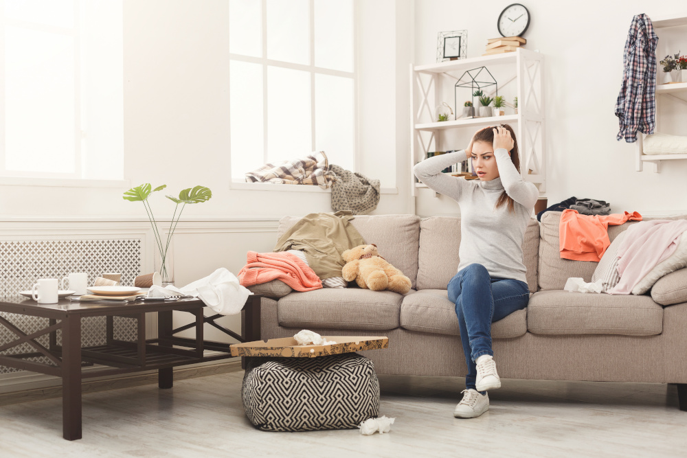 Desperate woman sitting on sofa in messy room