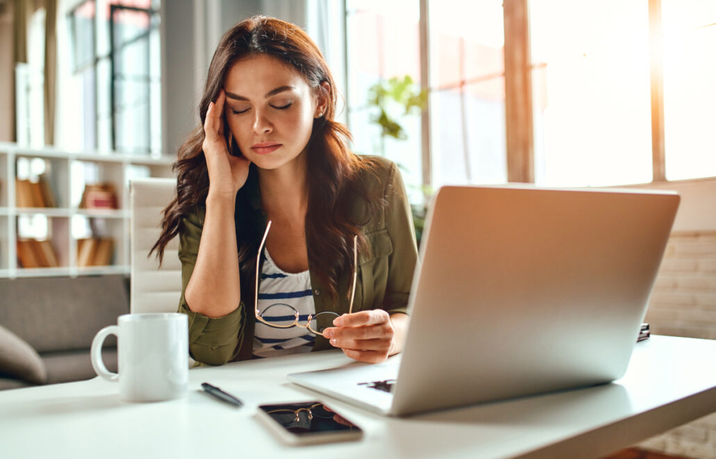 Tired business woman in stress works at a laptop while sitting a